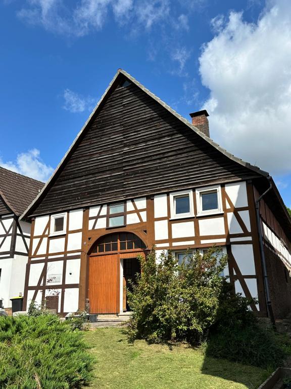 a house with a black roof and a wooden door at Anis Obsthof in Bad Arolsen