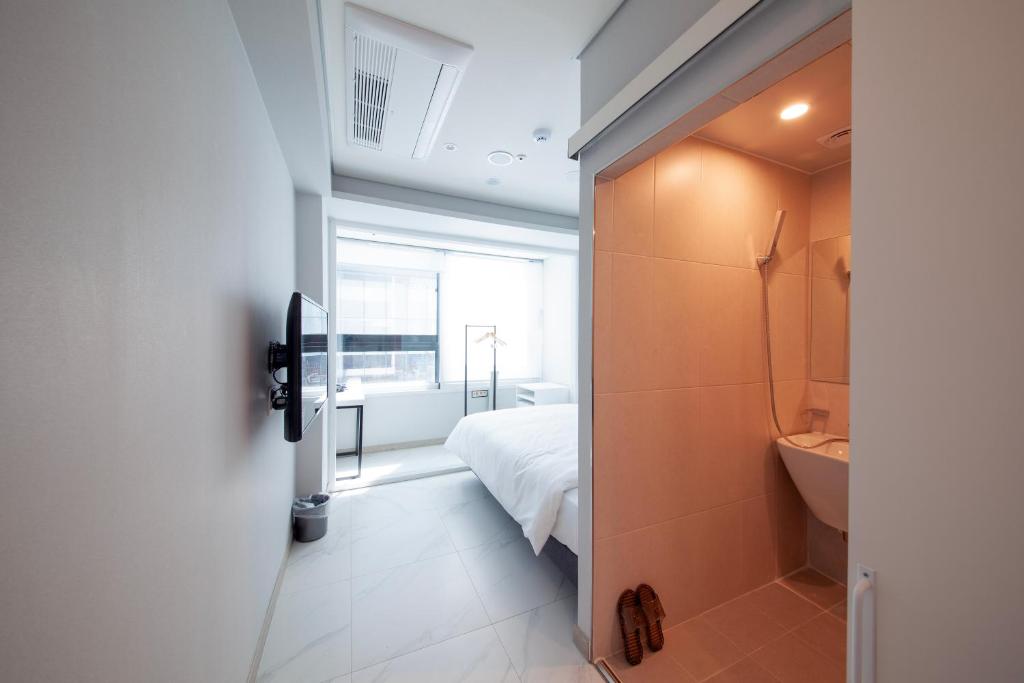 a bedroom with a bed and a bathroom with a window at K-Grand Hostel Sinchon in Seoul