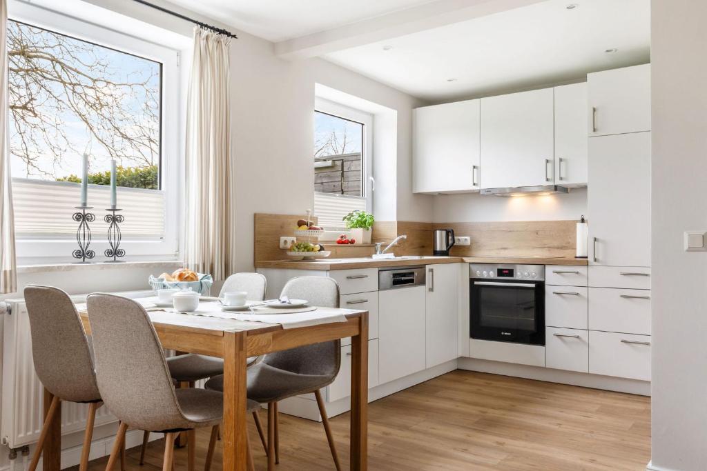 a kitchen with white cabinets and a wooden table and chairs at Backhaus Ost in Bisdorf