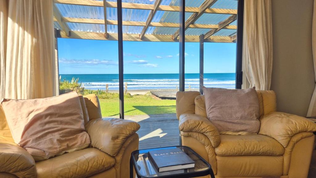 a living room with two chairs and a view of the ocean at Whareupoko in Waimarama