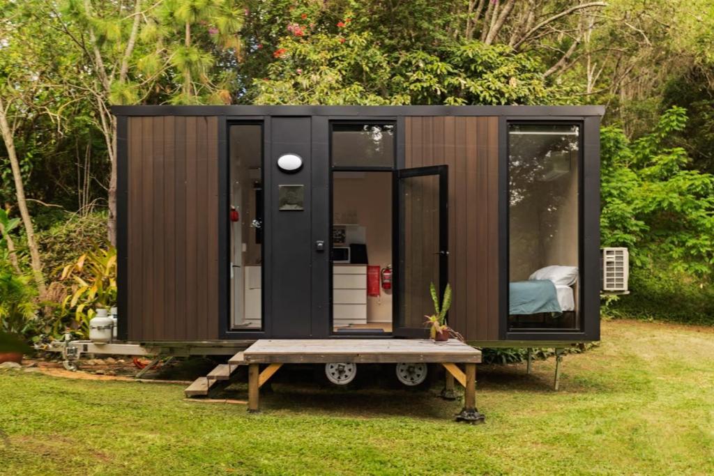 a black tiny house with a table in the grass at Natural Age by Tiny Away in Bahrs Scrub