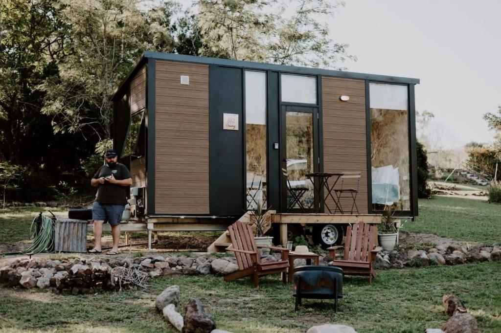 a man standing in front of a tiny house at Nomad Nation by Tiny Away in Mount Perry
