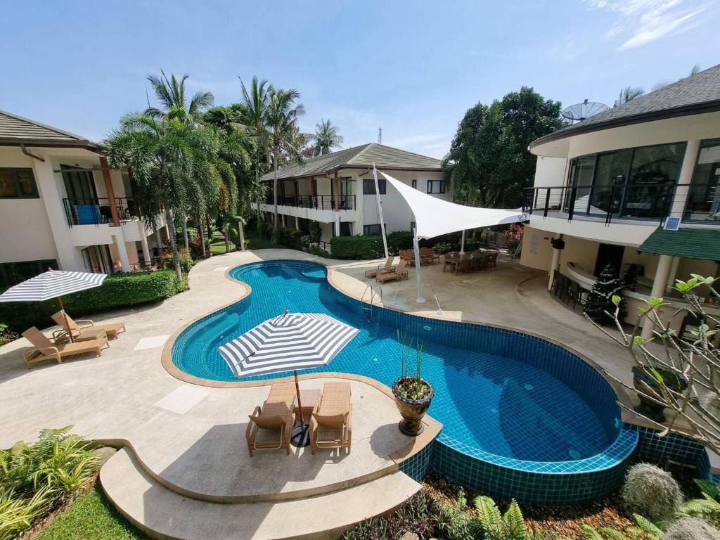 a swimming pool with chairs and umbrellas next to a building at Apartment Eliza Samui in Garden Resort with Shared Pool in Plai Laem