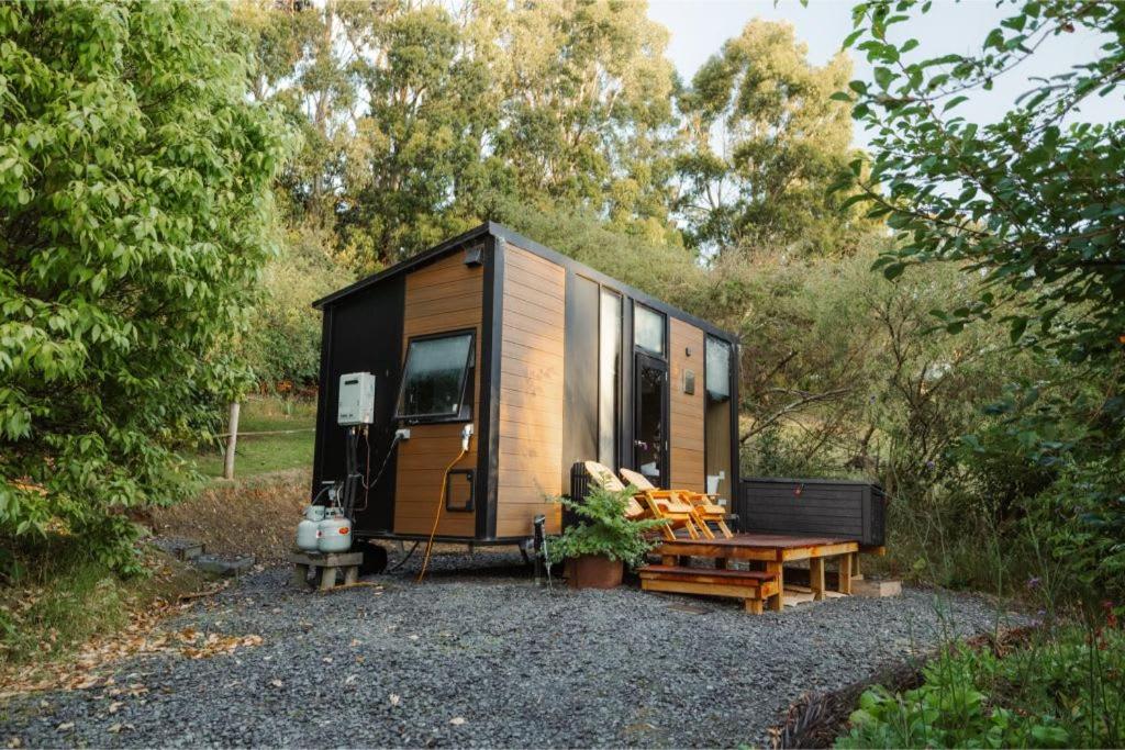 a wooden trailer with a bench and a table at Tranquility Tiny House by Tiny Away in Owaka