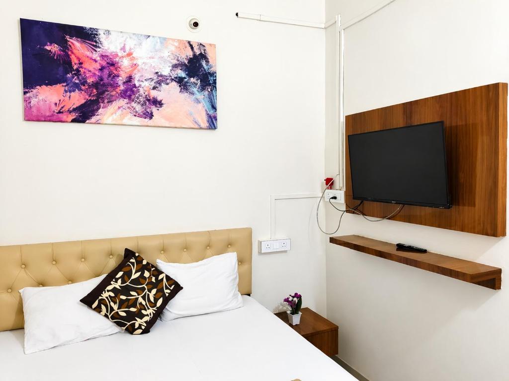 a bedroom with a bed and a flat screen tv at Hotel Mayur Lodge in Bijāpur