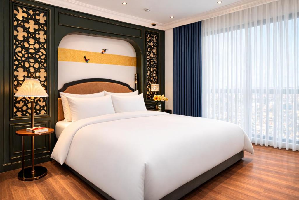 a bedroom with a white bed and a large window at Eli Suites in Hanoi