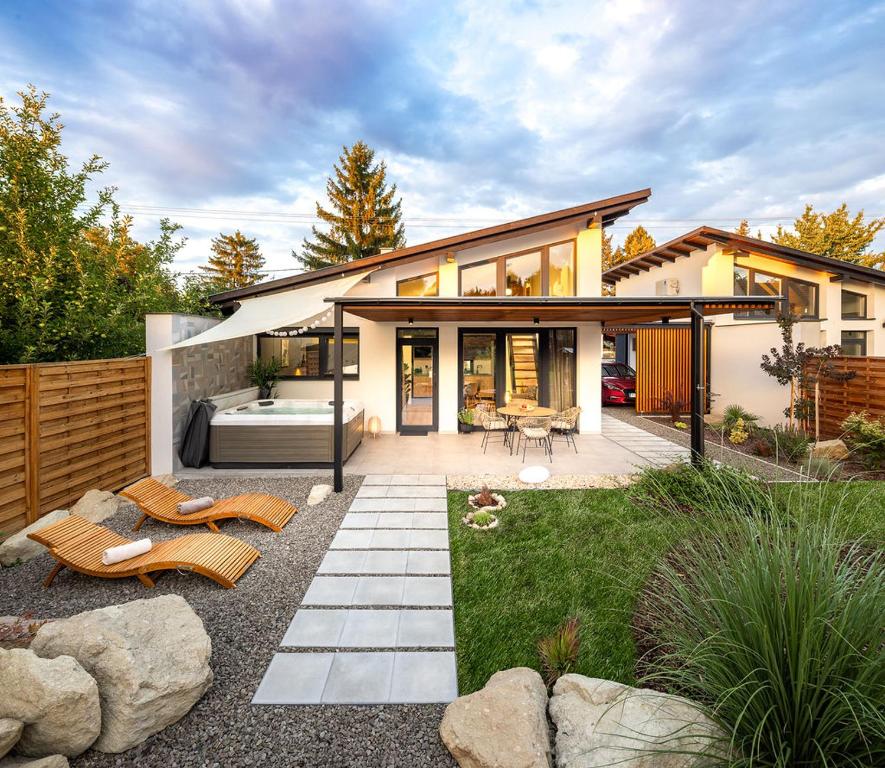 a house with a patio and a backyard with chairs at White Lotus Mini Loft House in Mezőkövesd