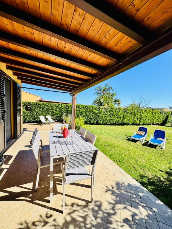a patio with a table and chairs under a wooden pergola at Villa Giovanna - Residence with Pool in Campofelice di Roccella