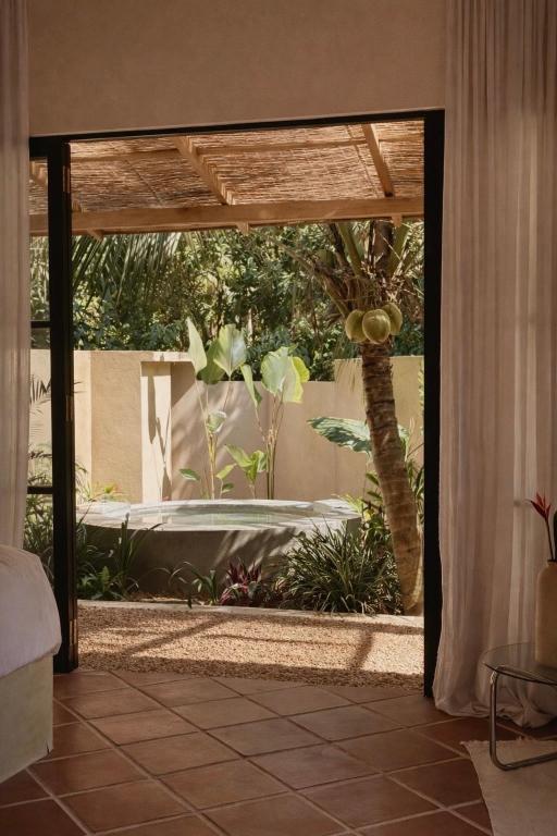 an open door to a garden with a palm tree at Design Cabin with Plunge Pool in Ahangama