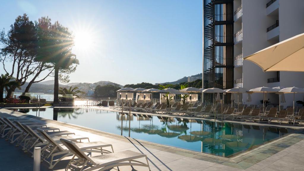 a swimming pool with lounge chairs and a hotel at Hotel Vibra Beverly Playa in Paguera