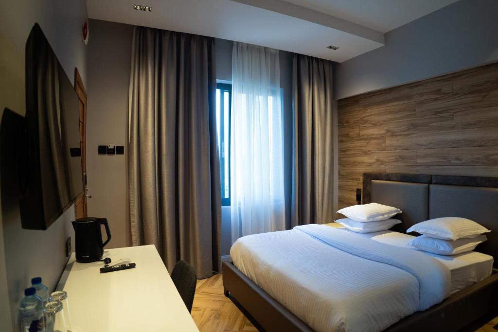 a bedroom with a bed with a desk and a window at Silverado Boutique Hotel in Tanga