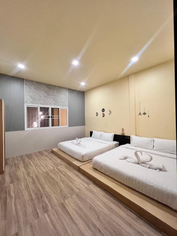 two beds in a room with wooden floors at Cozy Clover house in Hat Yai