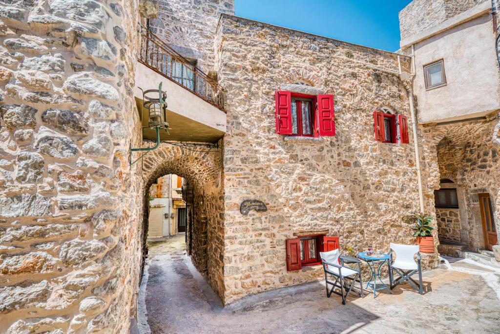 a stone building with red windows and a table and chairs at Mesaionas 1 in Olýmpoi