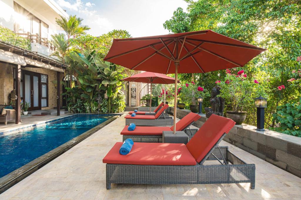 a group of chairs and umbrellas next to a swimming pool at The Magic Villa in Lebih