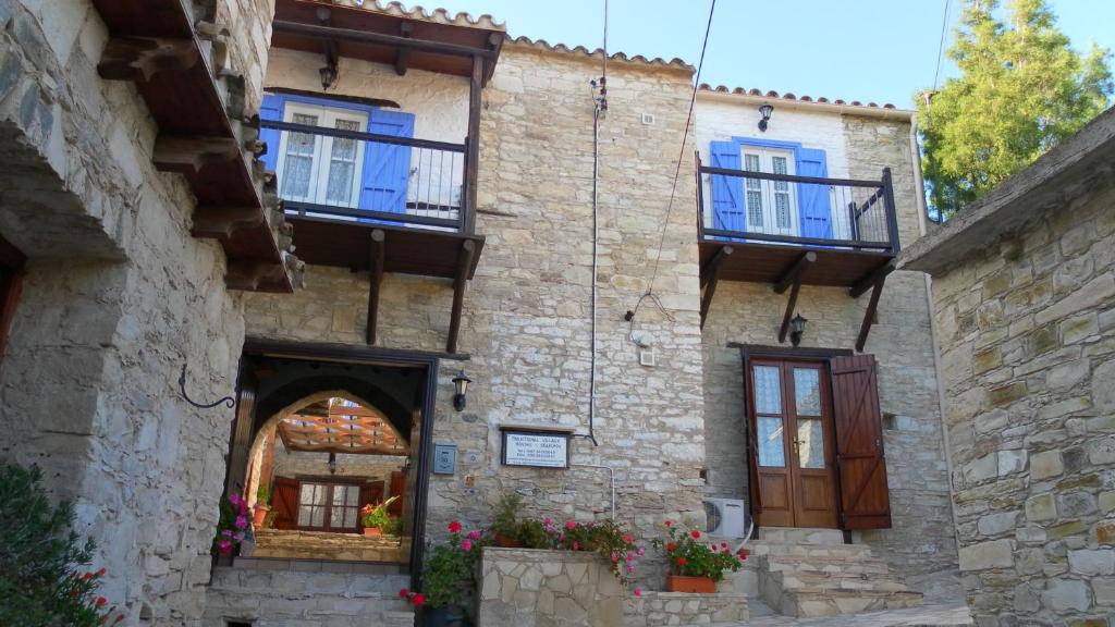 
a stone building with a clock on the side of it at Traditional Village Houses in Skarinou
