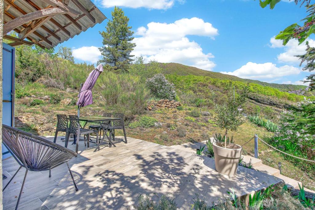 a patio with a table and chairs and an umbrella at Location Gîte Les Iris in La Robine