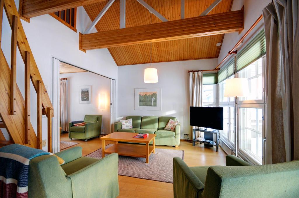 een woonkamer met groene meubels en een televisie bij Katinkulta Apartments in Vuokatti