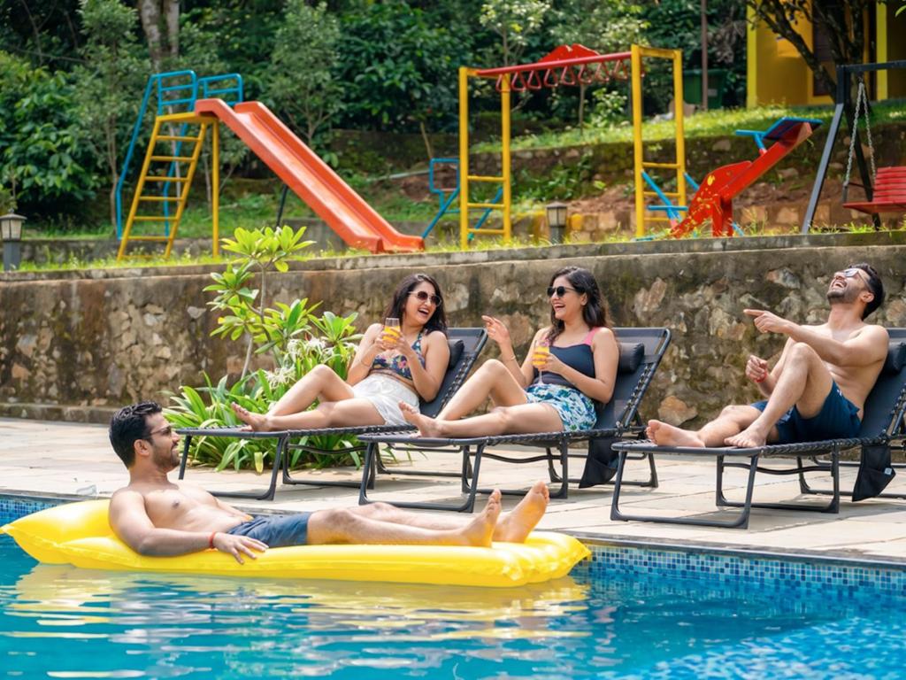 a group of people sitting in the swimming pool at The Hosteller Wayanad, Vythiri in Vythiri
