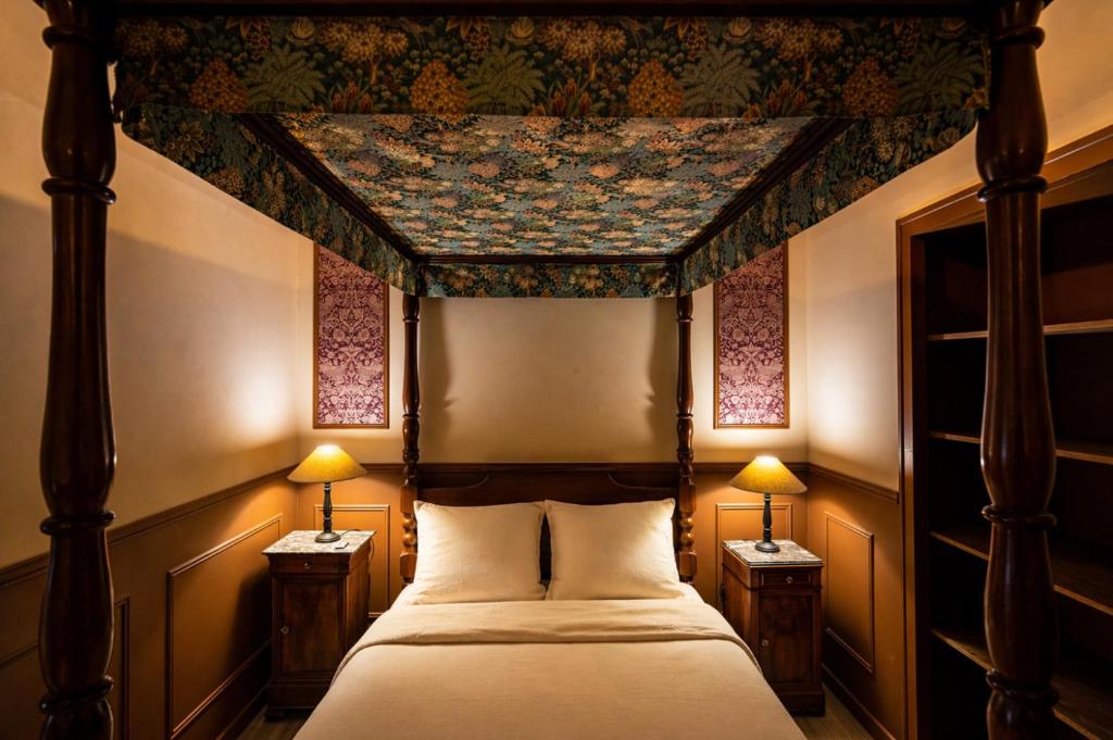 a bedroom with a canopy bed with two lamps at Le Logis des Seigneurs in La Flocellière