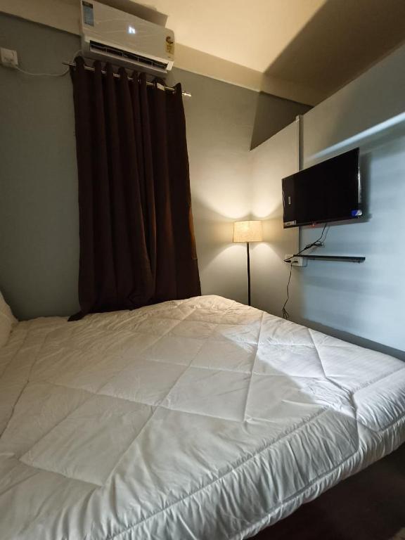 a bedroom with a white bed and a flat screen tv at Jonaki Aalay-Cozy and Budget Stay-Ulubari in Guwahati