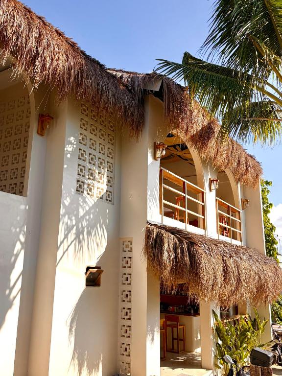 a house with a straw roof and a palm tree at Laya Boutique Hotel in General Luna
