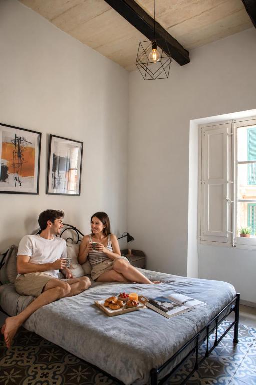 a man and a woman sitting on a bed at Iris -Paola Modern Townhouse in Paola