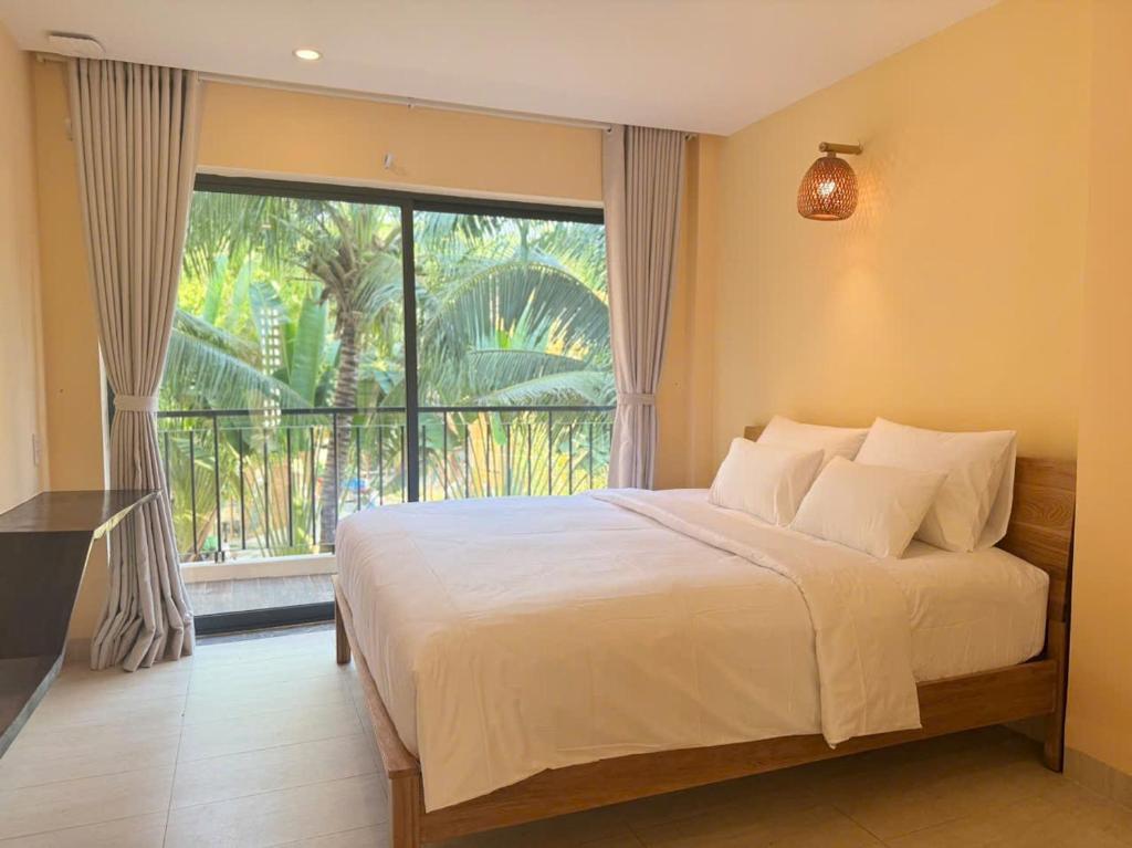 a bedroom with a large bed and a large window at Cham Riverside in Thôn Xuân Lạc