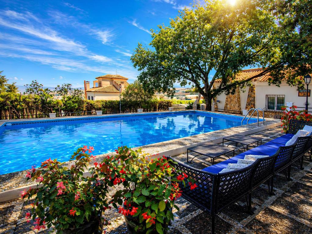 a swimming pool with benches and flowers in a yard at Casa Rural con piscina privada y jardines - LA CASILLA in Cájar