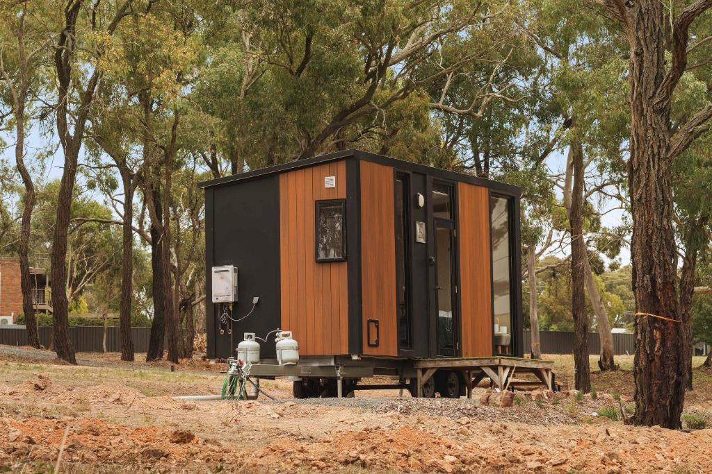 a tiny house sitting on a picnic table next to trees at Kiara By Tiny Away in Stawell