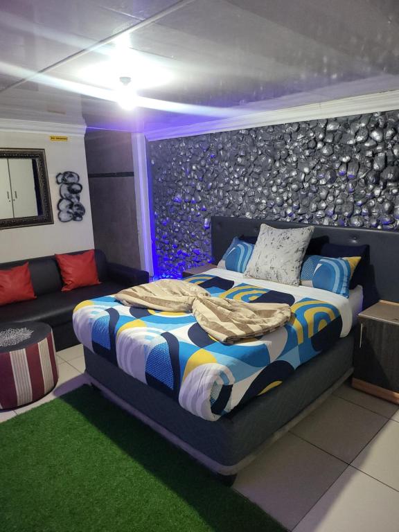 a bedroom with a bed and a couch at Tshedza Guest House in Pretoria