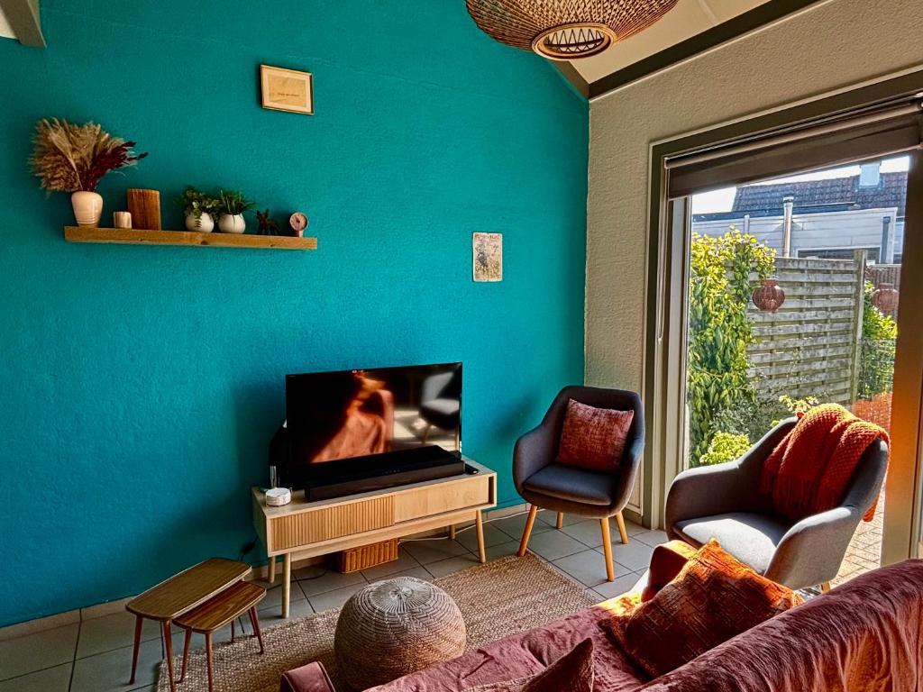 a living room with a couch and a flat screen tv at House & garden l'Hippodrome in Bredene