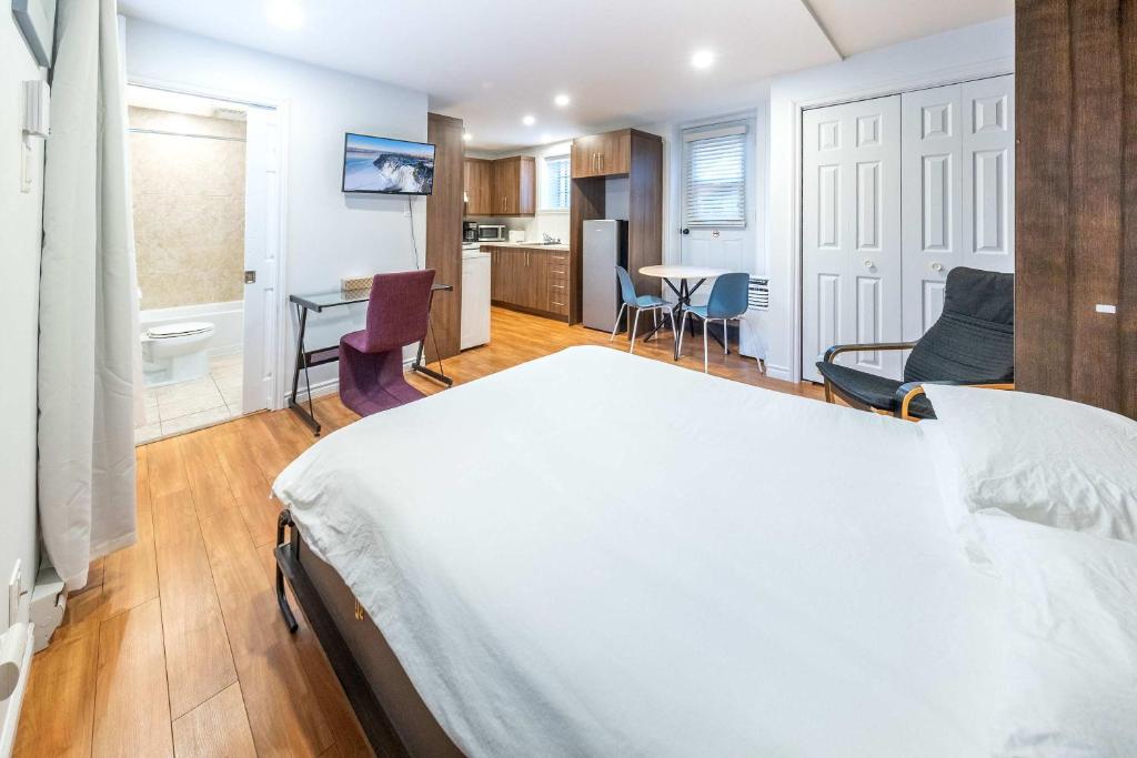 a bedroom with a white bed and a kitchen at Near the Ferry - Studio de charme in Lévis