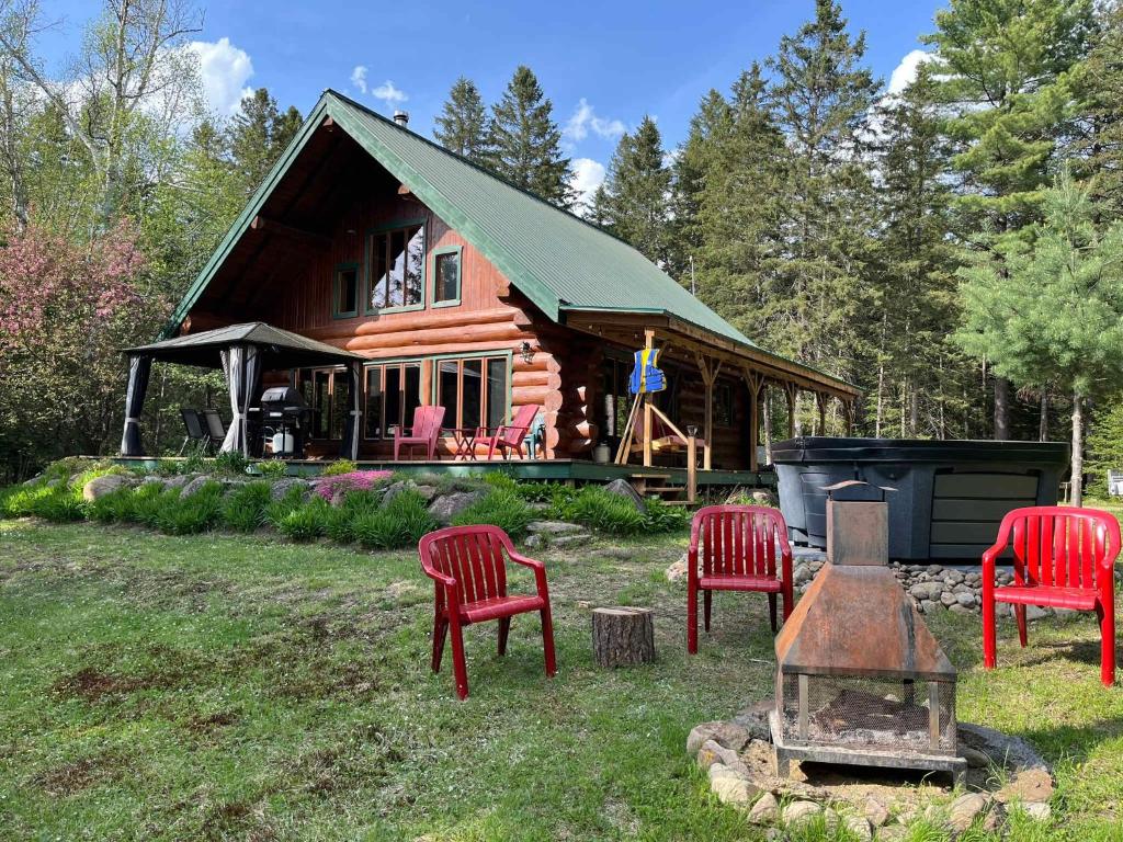 a log cabin with red chairs and a grill at Spa & River - Hidden chalet - Chalet cache in Saint-Alexis-des-Monts