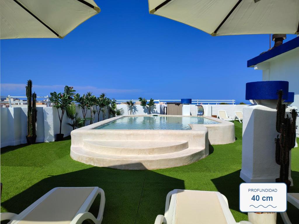 ein Swimmingpool mit Stühlen und Sonnenschirmen auf einem Rasen in der Unterkunft Hotel Porto in Gandía