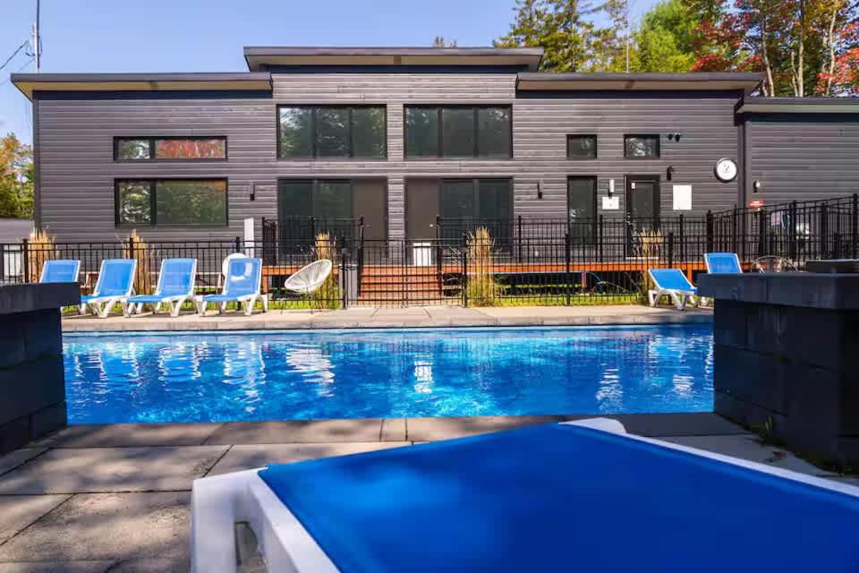 a house with a swimming pool in front of a building at Pool Spa sauna & Pool Table - Beaulieu 110 in Pont-Rouge