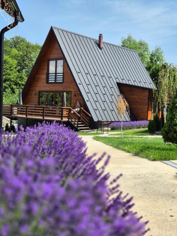 a wooden house with purple flowers in front of it at Twin Cabins / Cabanele Gemene in Suceava