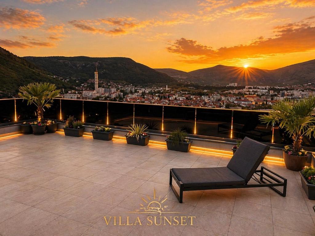 a chair on a balcony with a view of a city at Villa Sunset Mostar in Mostar