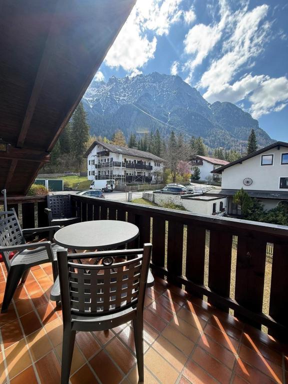 a table and chairs on a balcony with a view of mountains at Karwendel Lodge in Mittenwald