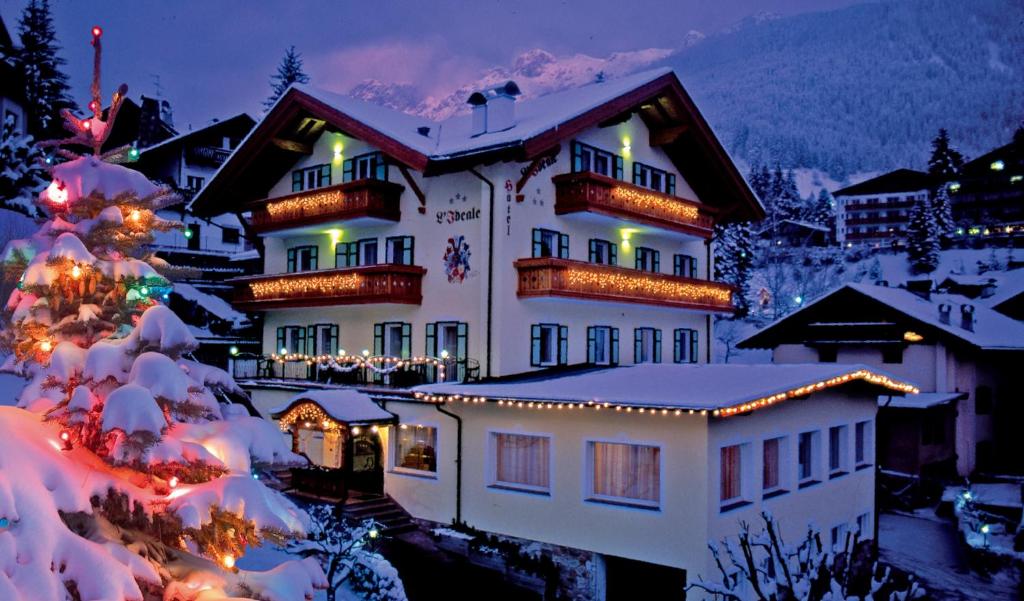 un edificio cubierto de luces de Navidad en la nieve en Hotel L'Ideale, en Moena