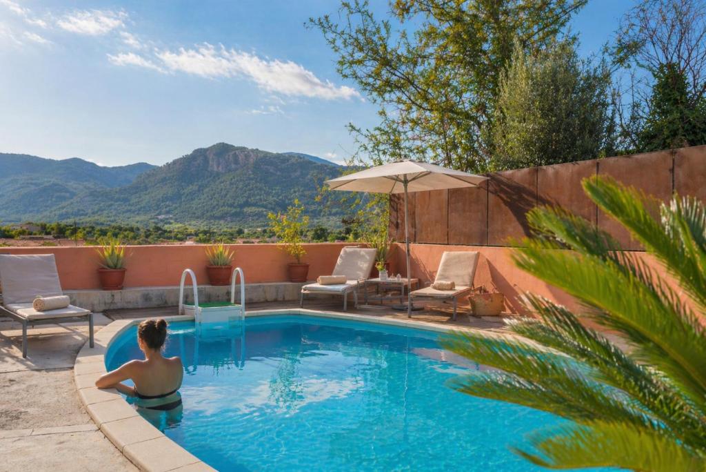 a woman in a swimming pool with a view of mountains at Hotel Moscari Nature & Wellness by CheelHotels in Moscari