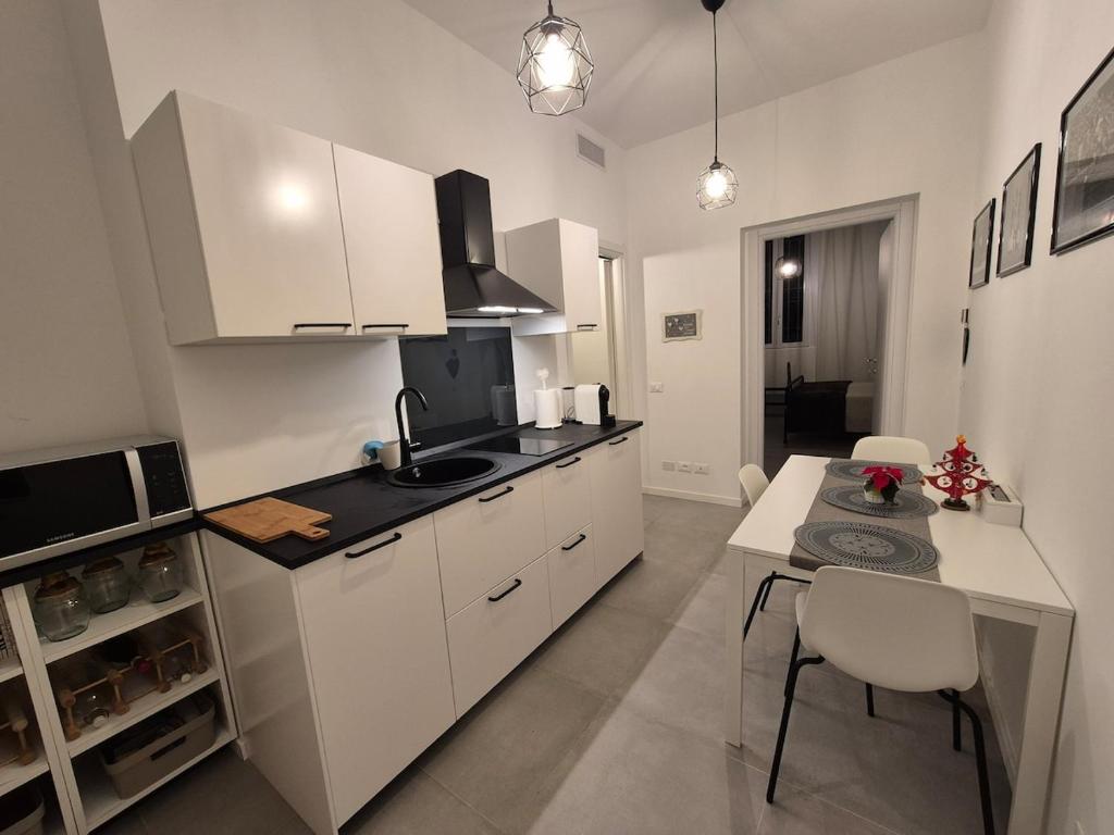 a kitchen with white cabinets and a table with chairs at Casetta della Lupa in Cernusco sul Naviglio