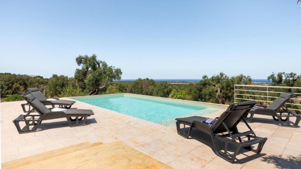 a swimming pool with two chairs and a swimming pool at The Ridge House with Sea View by Rentbeat in Carovigno