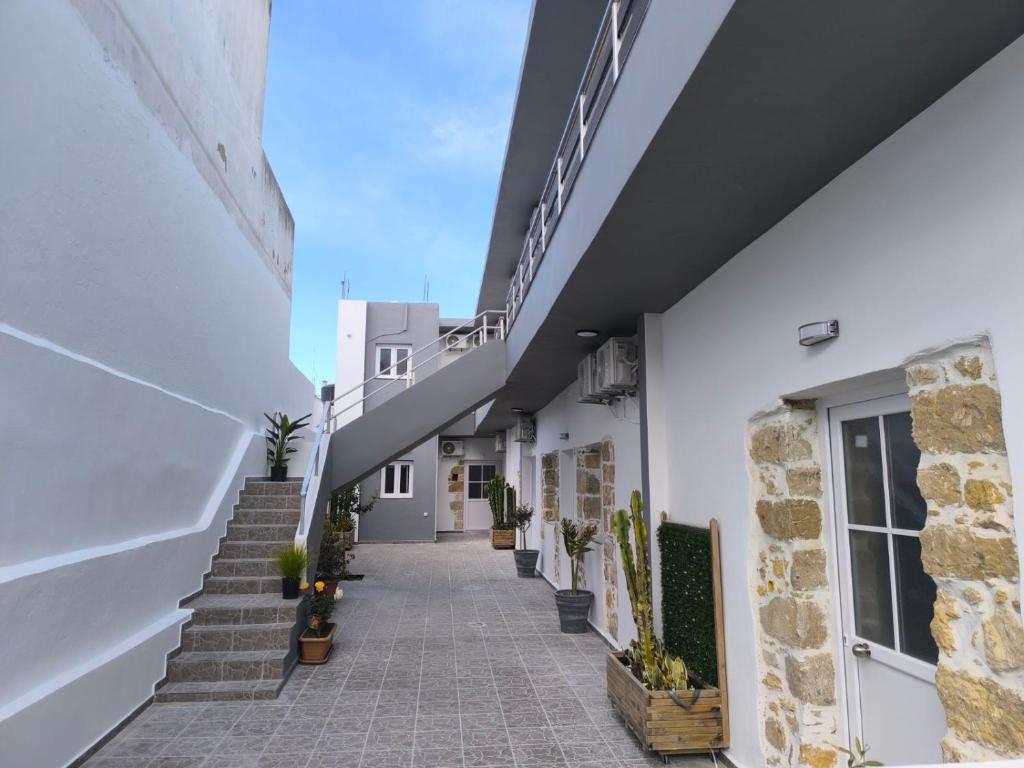 a hallway of a white building with stairs and potted plants at Veniro Luxury Apartments in Moírai