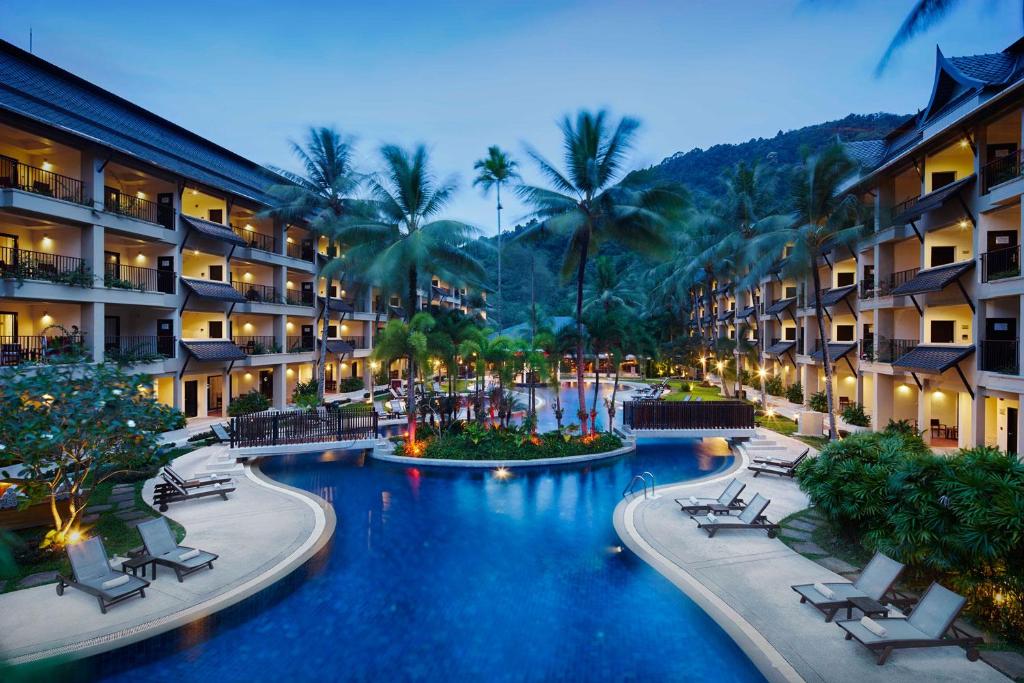 a resort with a pool with chairs and palm trees at Radisson Resort and Suites Phuket in Kamala Beach
