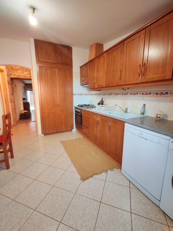 a kitchen with wooden cabinets and a white dishwasher at Stone House - Waterfalls, Nature Stay in Louriçal do Campo