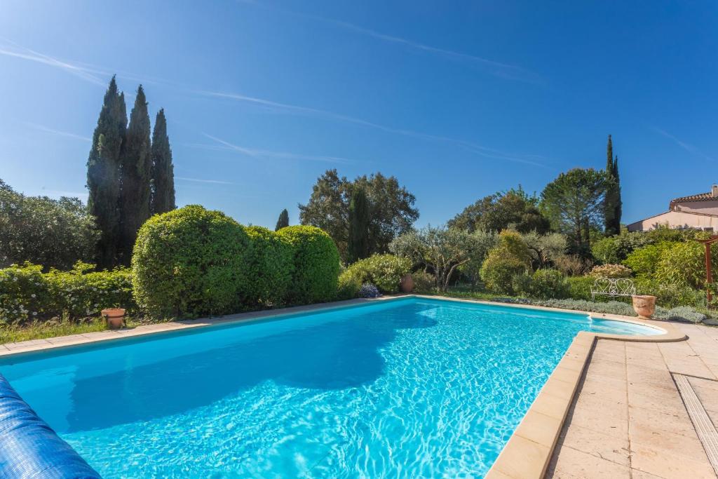 ein Swimmingpool in einem Garten mit Bäumen und Sträuchern in der Unterkunft Bastidon Cotignac in Cotignac