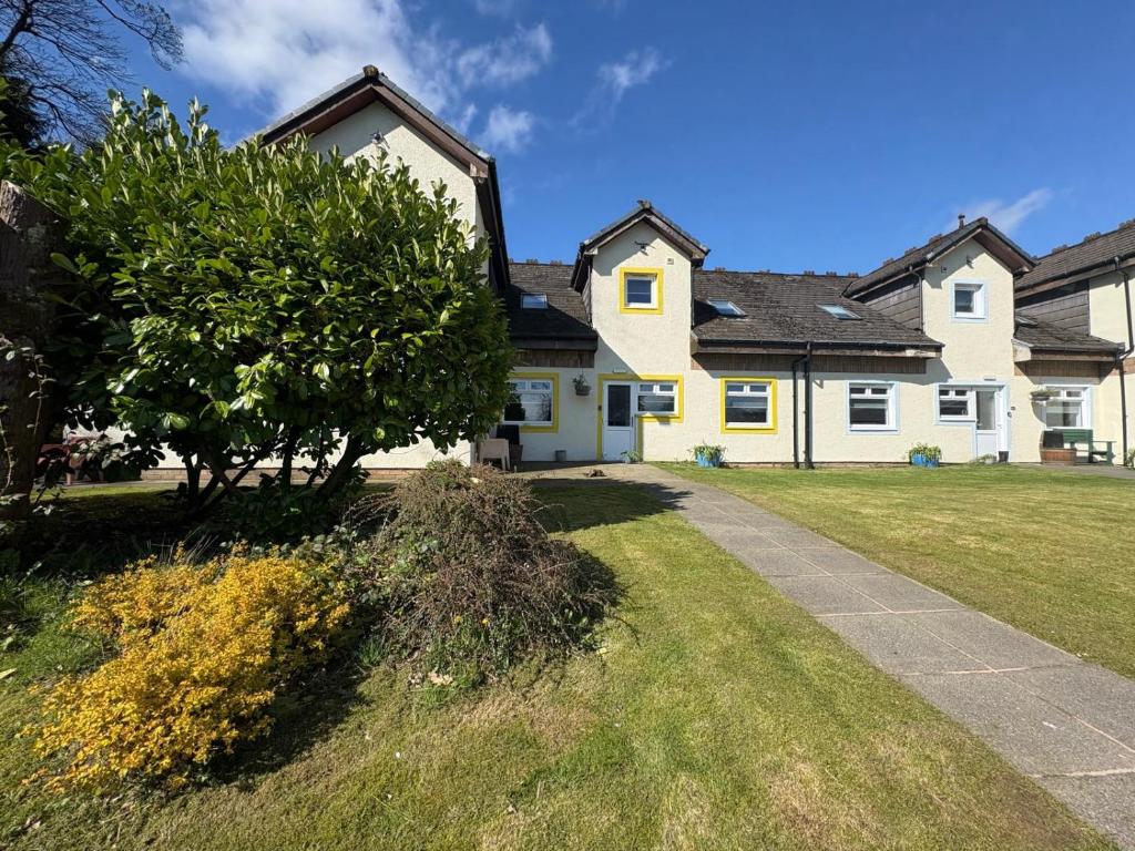 a white house with a tree in the yard at Cunninghame 3 in Beith