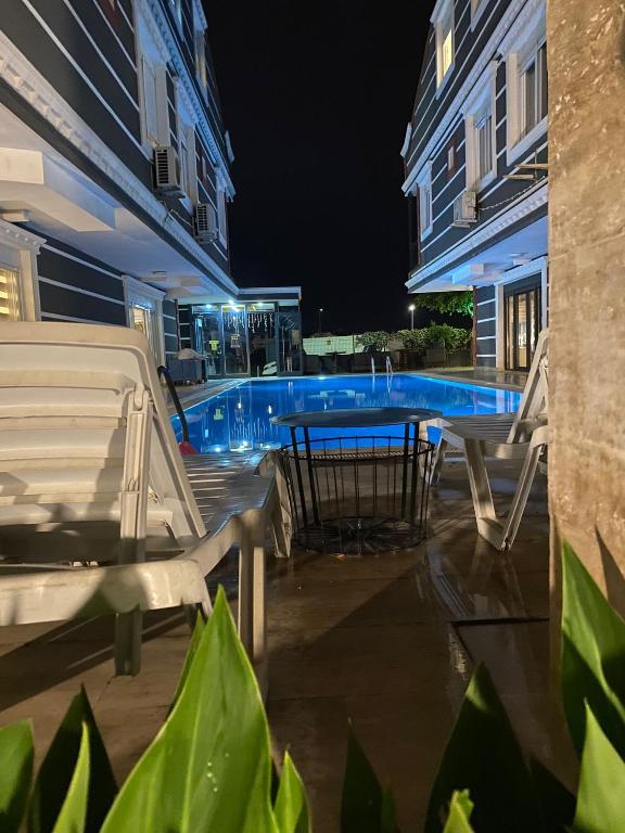 a table and chairs next to a swimming pool at night at Avullar Palace Hotel in Antalya