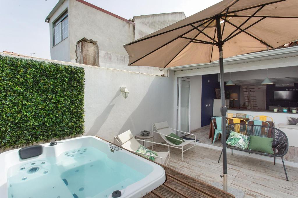 a bath tub sitting on a deck with an umbrella at Casa Tejo Villa com Jaccuzi in Valada
