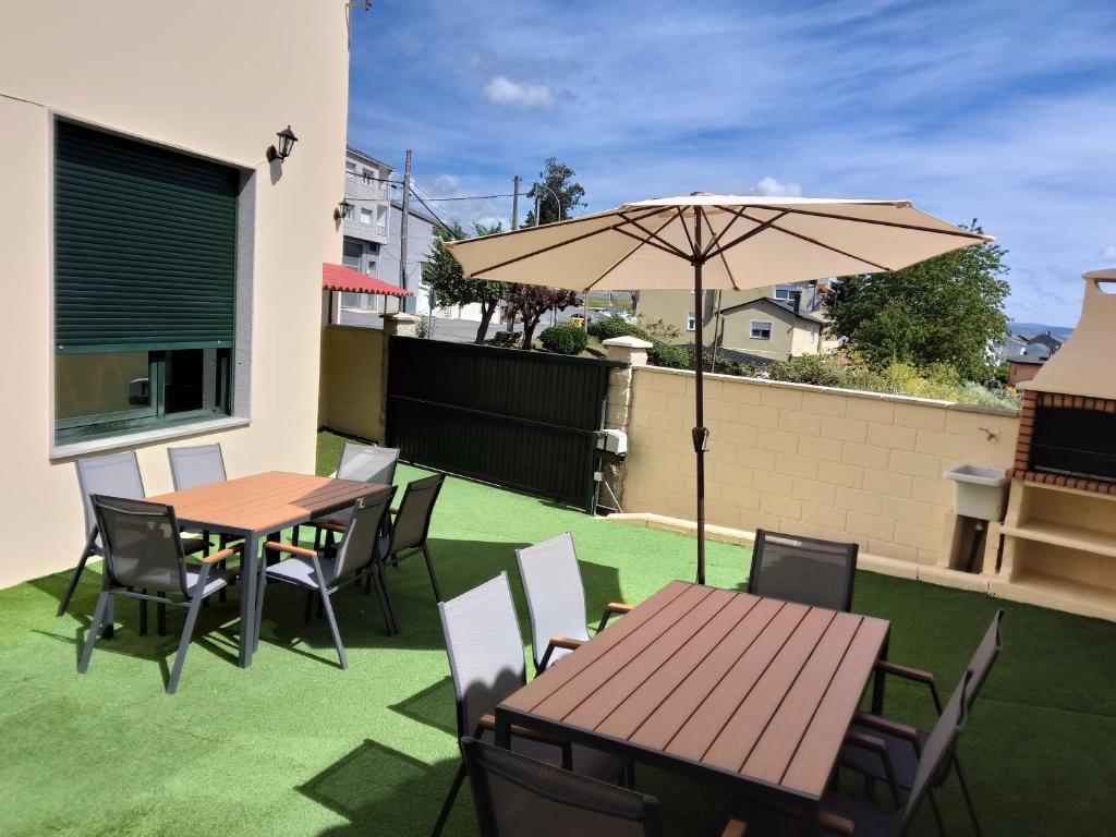 a patio with tables and chairs and an umbrella at Pensión Casa Rego Sarria in Sarria